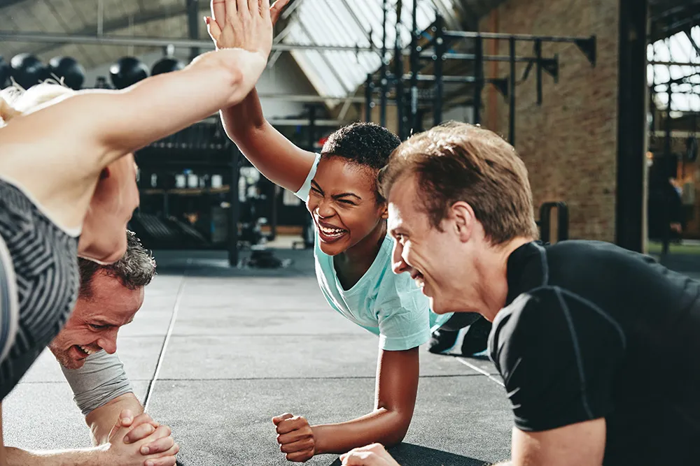 Diverse group of friends laugh while working out at a gym