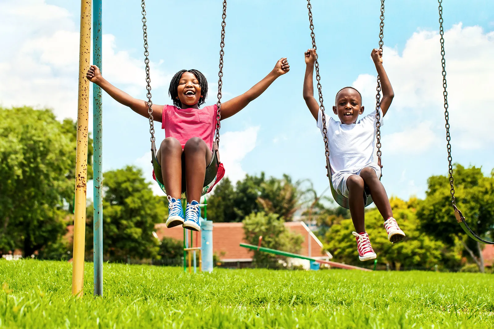 Two children ride swings at park