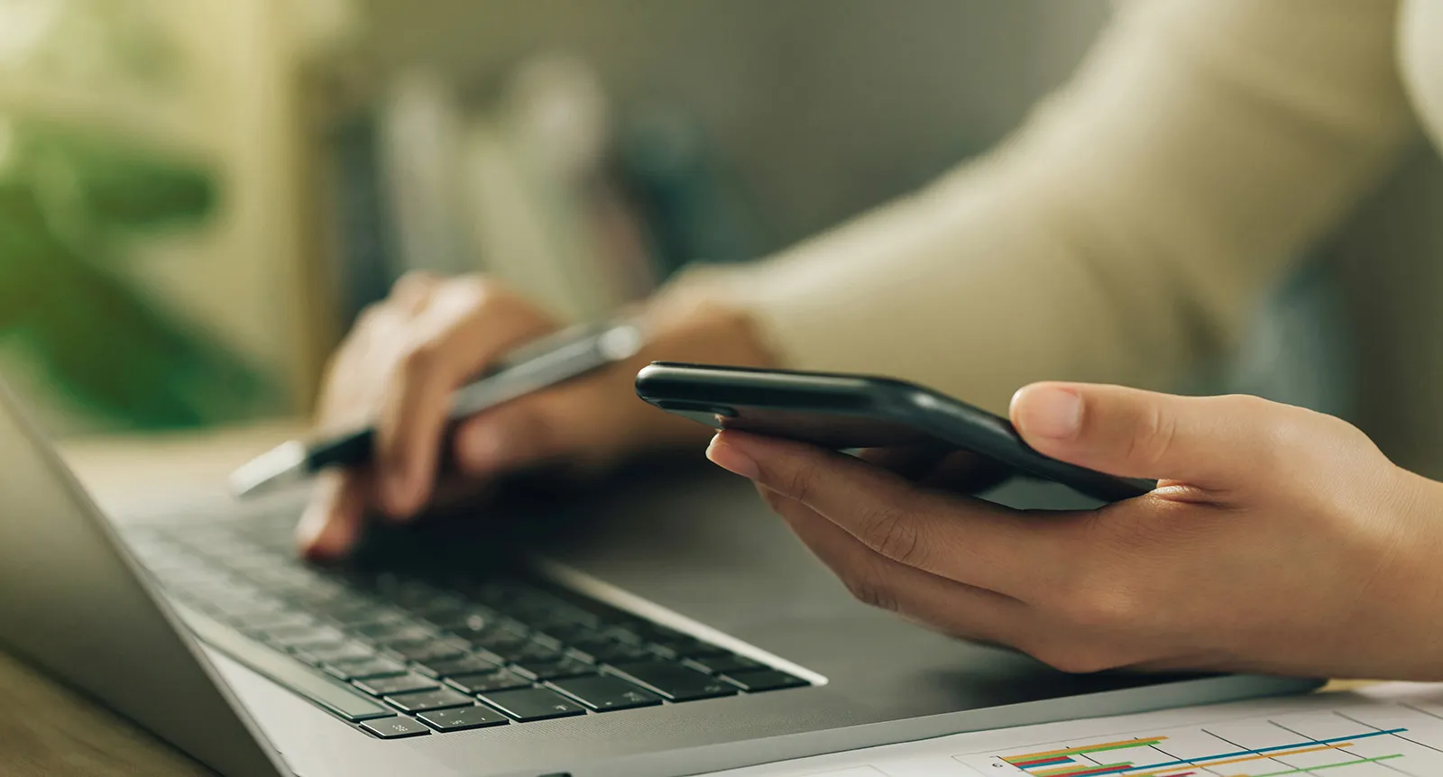 Woman checks cell phone and computer