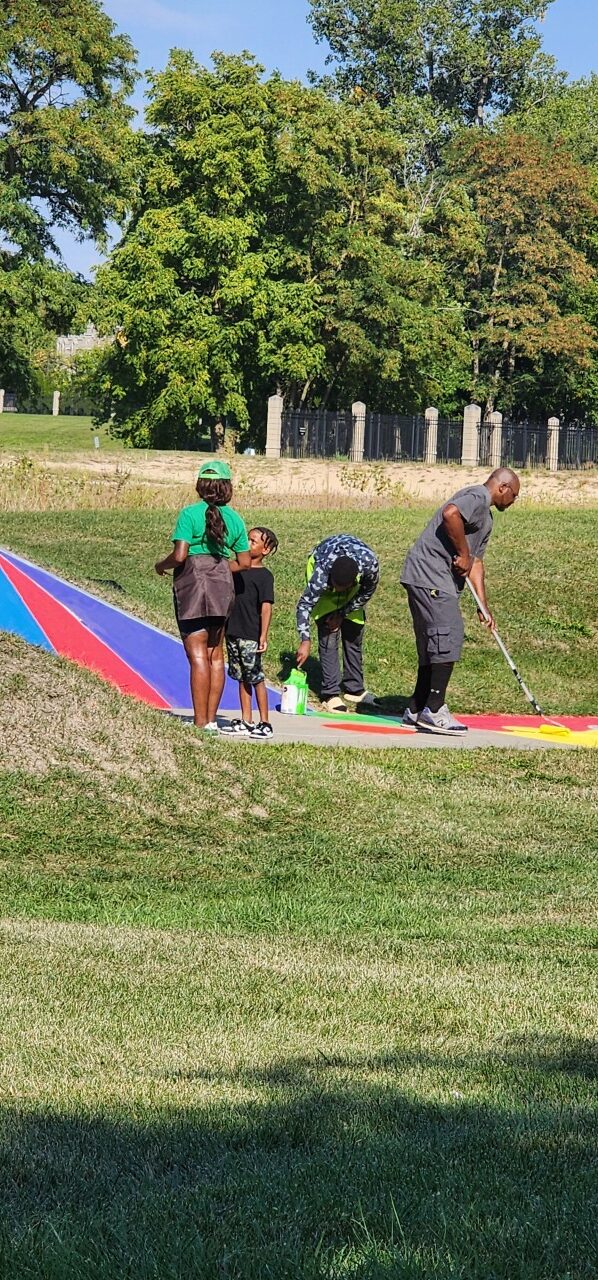 A family painting a colorful community pathway together in a park